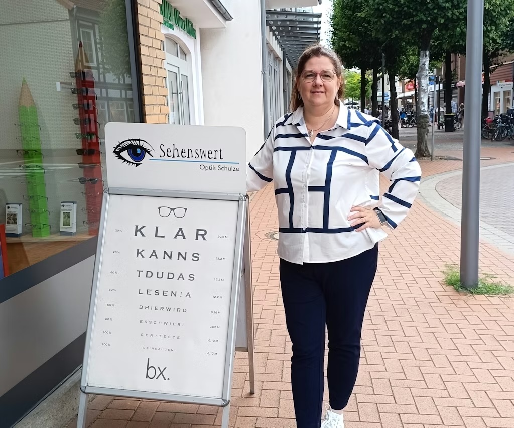 Mitarbeiterin von Sehenswert Optik Schulze neben einem Werbeaufsteller